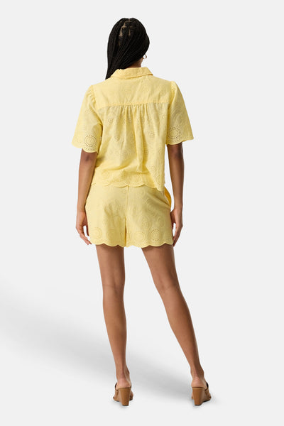 Chemise à manches courtes jaune de GARCIA en broderie anglaise avec bords festonnés, portée avec un short assorti, vue de dos.