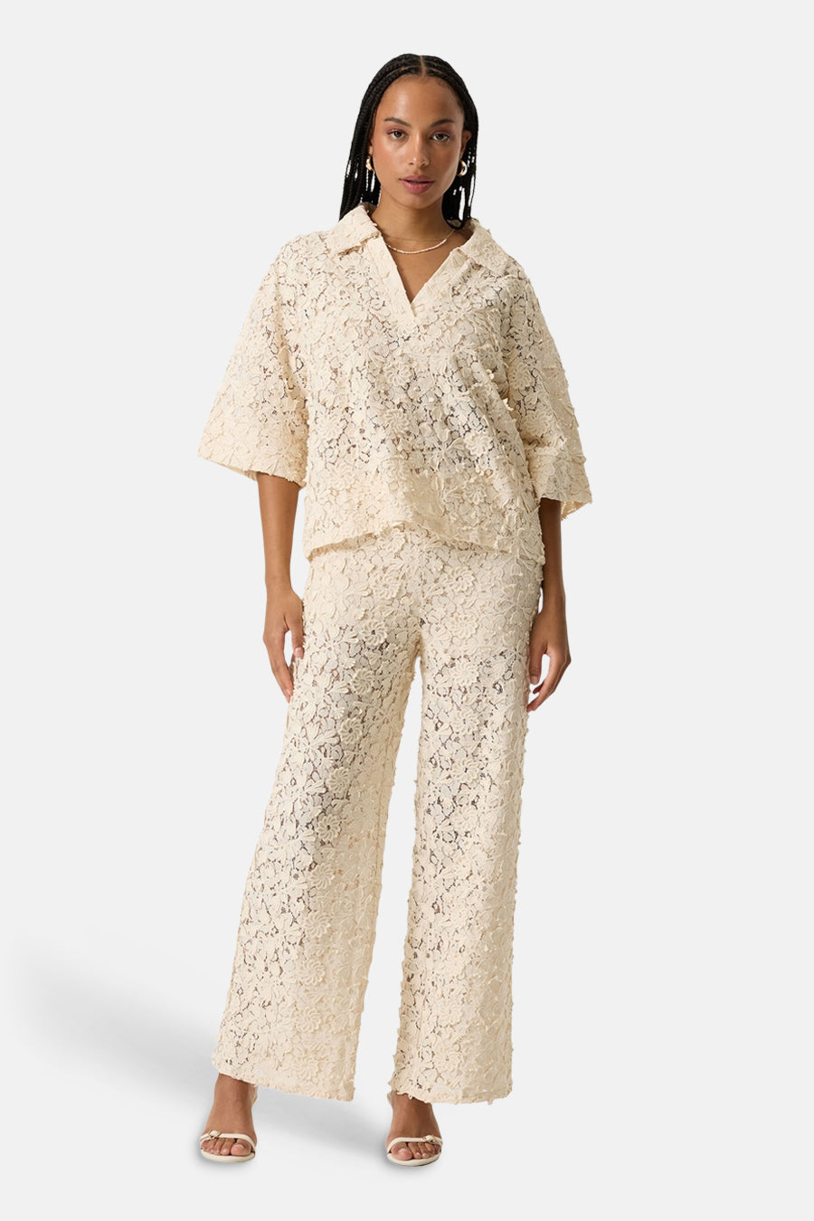 Chemise à manches courtes beige de GARCIA en dentelle florale texturée, avec col V, portée avec un pantalon assorti.