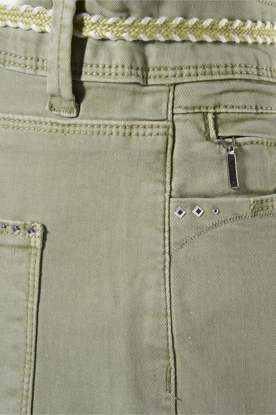 Pantalon vert par ZABAIONE avec ceinture tressée, poche zippée et rivets décoratifs.
