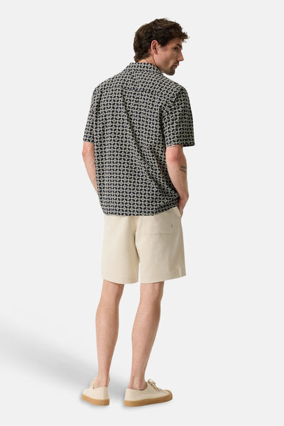 Multicolored short-sleeve chemise with geometric print, back view, worn with beige shorts and white sneakers