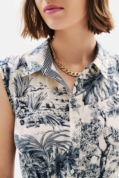 Robe multicolore de CAROLL à motifs tropicaux et fermeture boutonnée, portée avec un collier doré.
