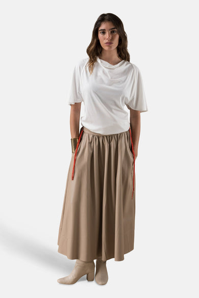 Wit T-shirt met korte mouwen van ADORE, gedragen met een lange beige rok en bijpassende enkellaarsjes.