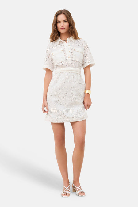 Witte kanten jurk van CAROLL, met korte mouwen en riem, gedragen met sandalen met bandjes.
