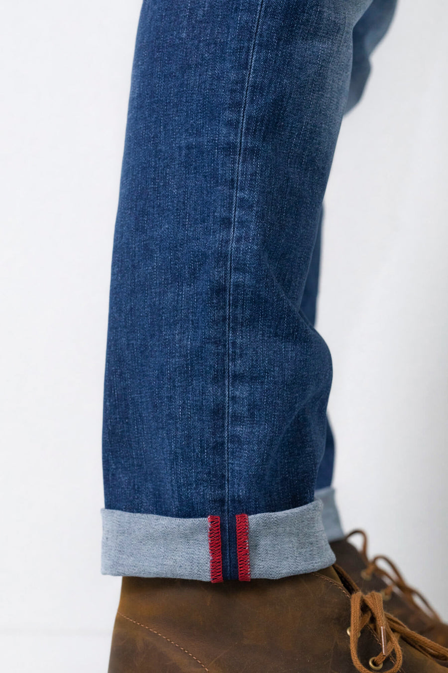 Jean fuselé bleu moyen de Petrol Industries®, avec ourlet retroussé et coutures rouges visibles.