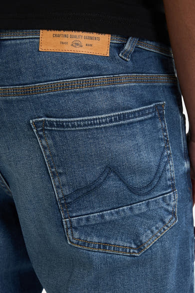 Jean fuselé bleu moyen de Petrol Industries, avec une poche arrière détaillée et étiquette en cuir.