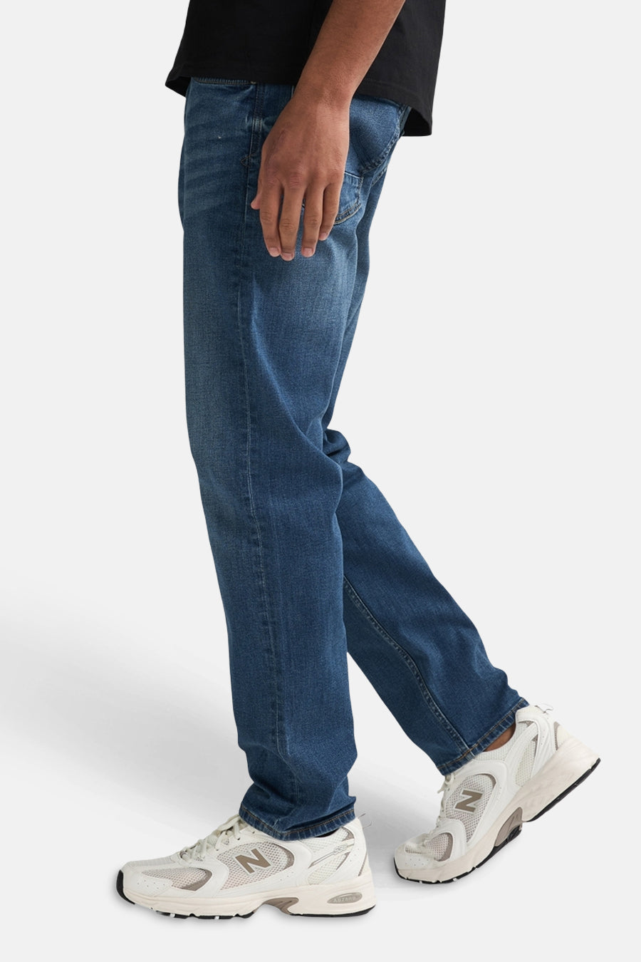 Jean fuselé bleu moyen de Petrol Industries, porté avec des baskets blanches et un t-shirt noir.