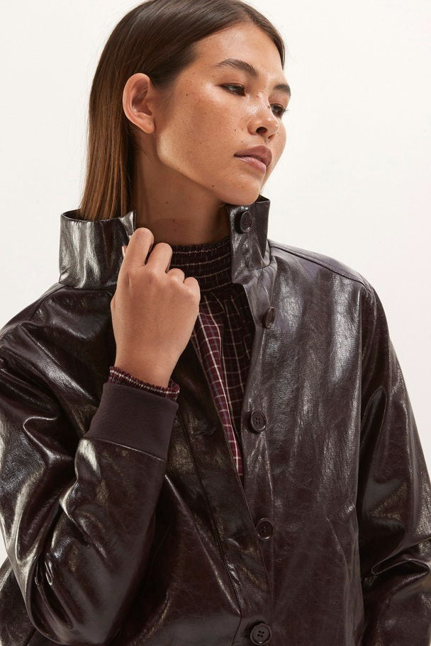 Veste violet en cuir synthétique brillant par SENSO, col montant boutonné, vue de profil sur modèle portant chemise à carreaux.