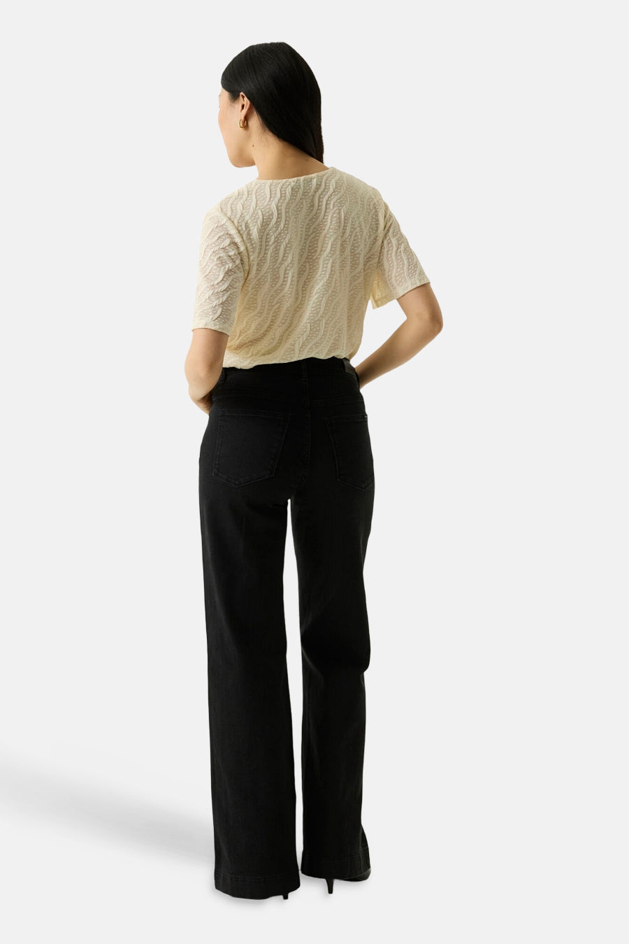 Ecru short-sleeve textured top with wavy pattern, back view, paired with black wide-leg pants