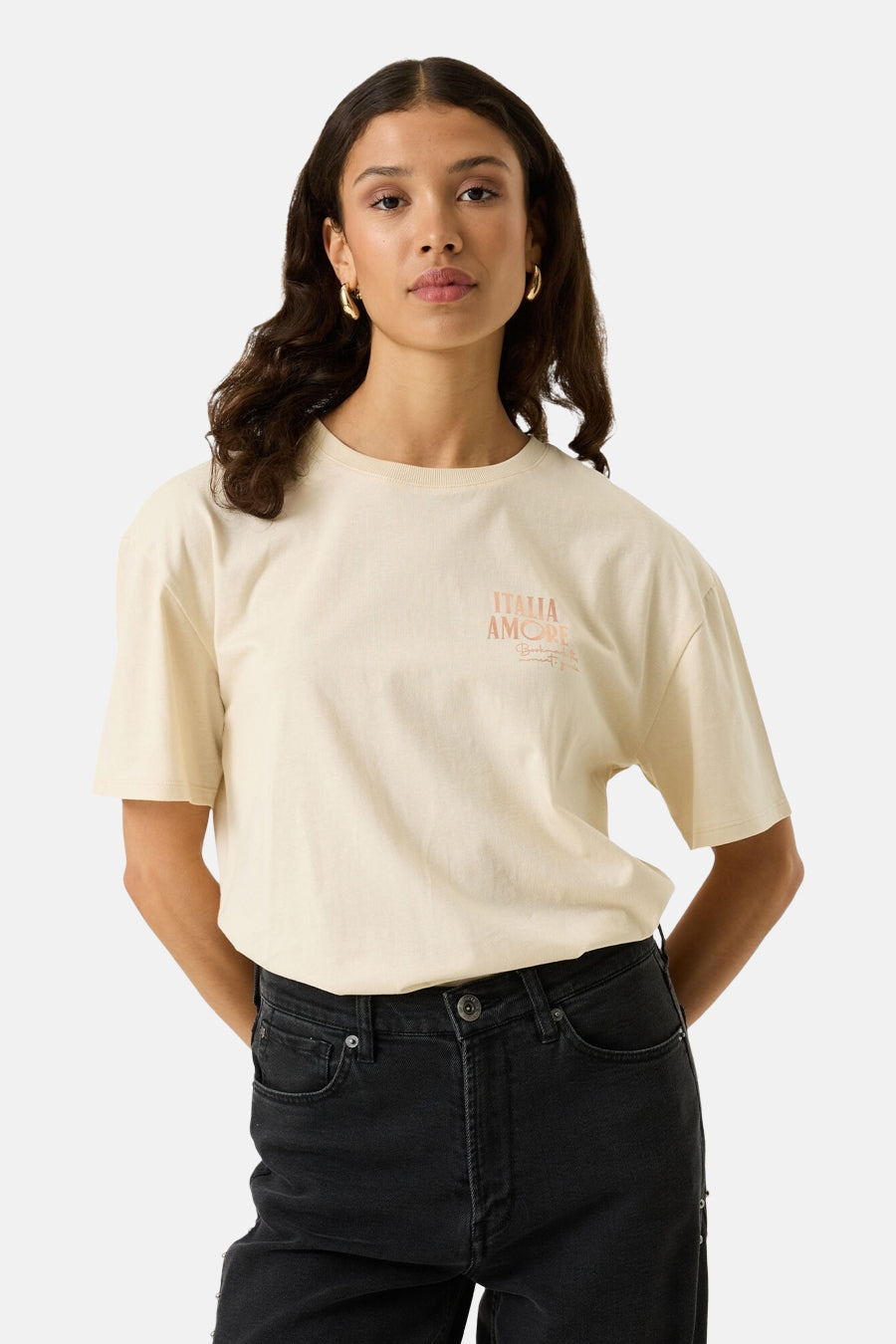 Ecru short-sleeve t-shirt with small orange "ITALIA AMORE" print on chest, worn with black jeans, front view
