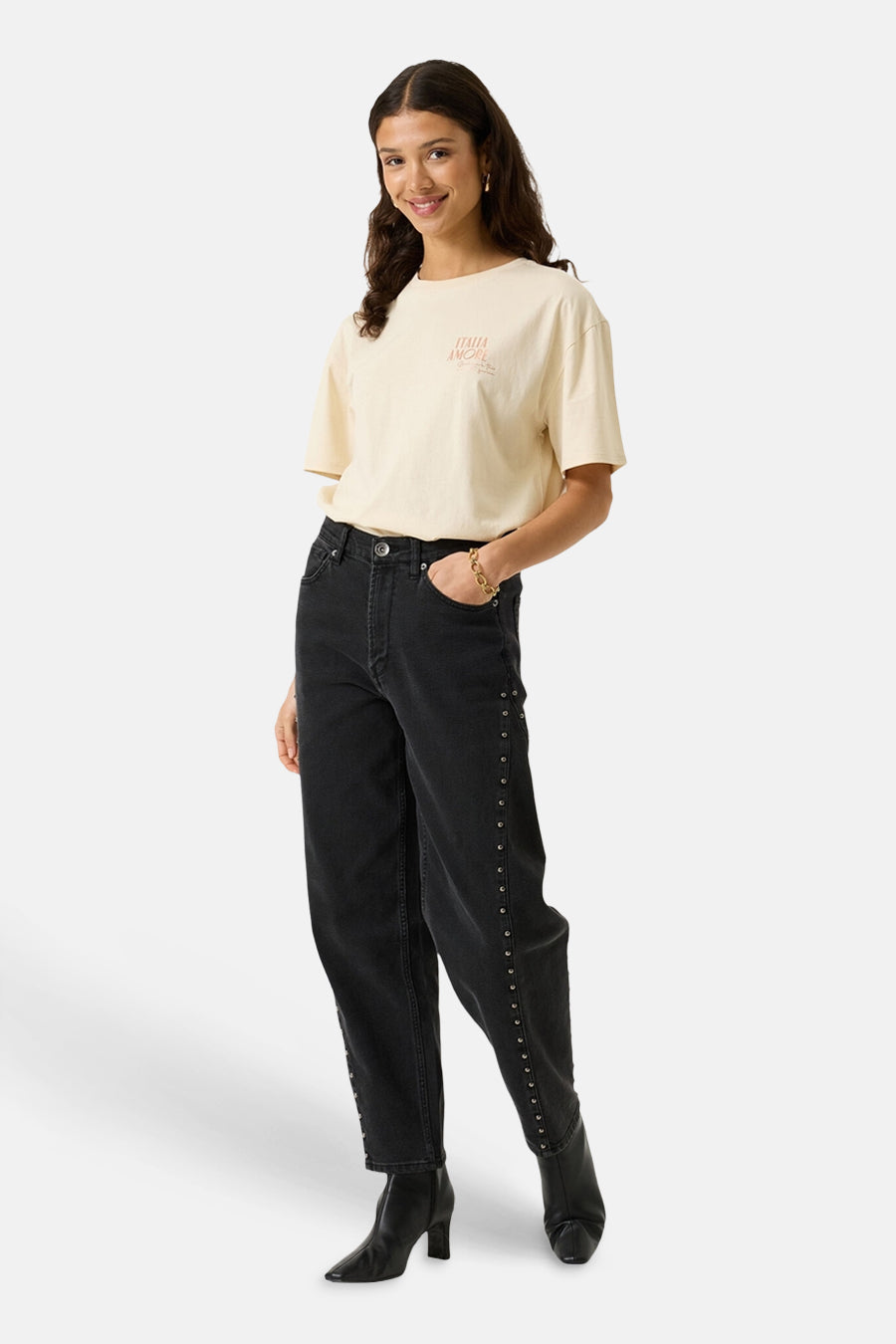 Ecru short-sleeve t-shirt with small chest print, worn with black studded jeans and ankle boots, full-length front view