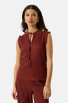 Terracotta ribbed sleeveless blouse with ruffled shoulder details and front tie neckline, worn with matching pants and gold jewelry, front view
