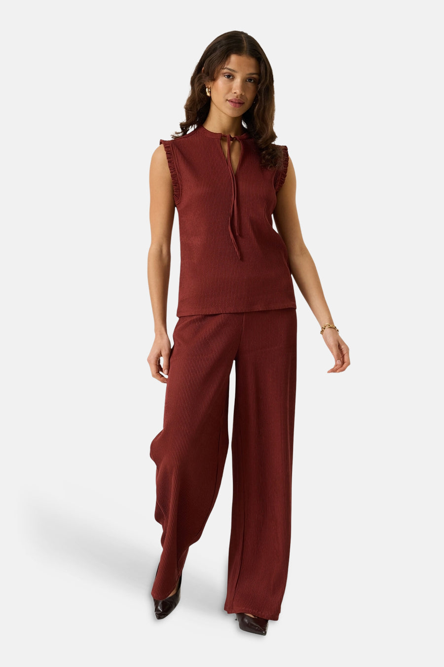 Terracotta ribbed sleeveless blouse with ruffled armholes and front tie, paired with matching wide-leg trousers, full-length lifestyle view