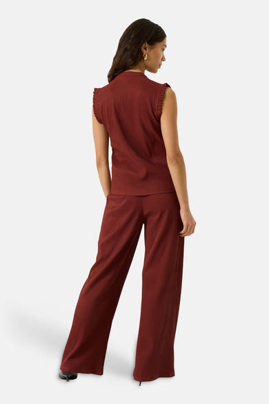 Terracotta ribbed sleeveless blouse with ruffled shoulder details, back view, paired with matching wide-leg trousers