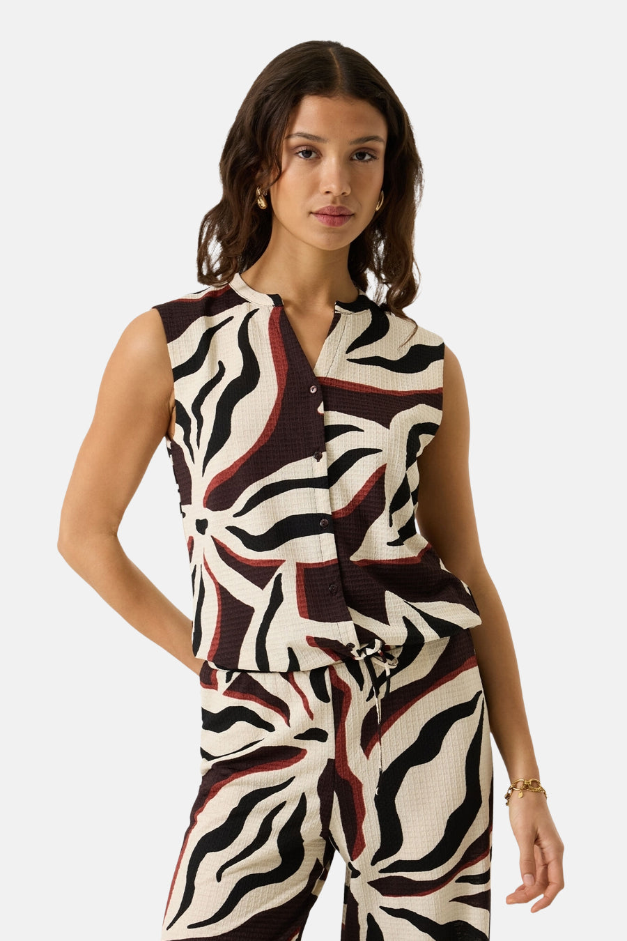 Multicolored sleeveless blouse with bold abstract print, front buttons, and textured fabric, worn with matching pants in a lifestyle front view