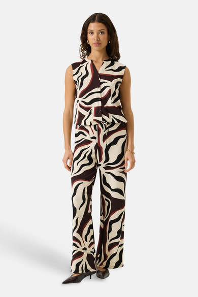 Multicolored sleeveless blouse with bold abstract pattern, front button closure, and ribbed texture, shown in full-length lifestyle view.