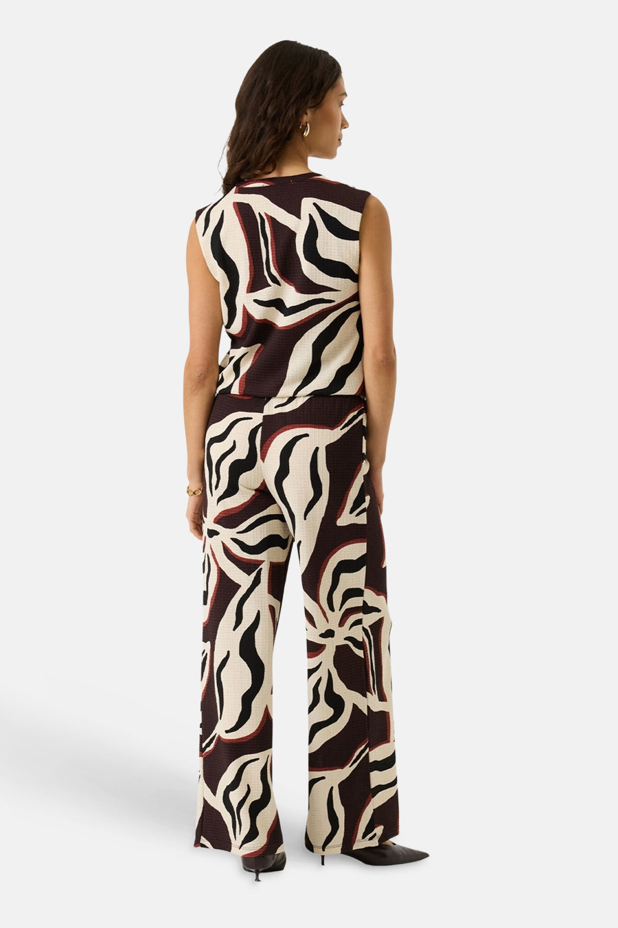 Multicolored sleeveless blouse with abstract wave pattern, back view, paired with matching wide-leg pants and black heels