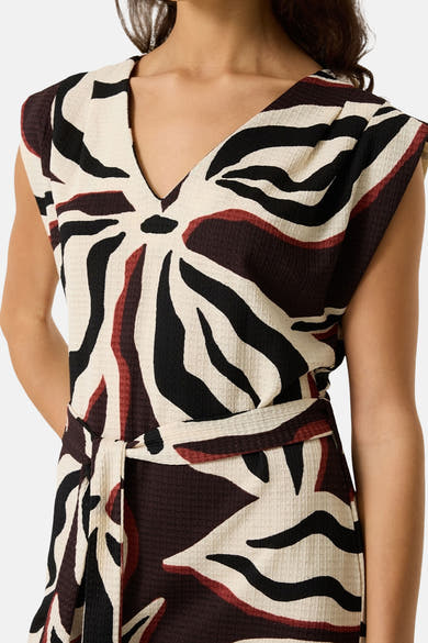 Multicolored sleeveless wrap dress with bold black, white, and red abstract pattern, textured fabric, V-neckline, and tie waist, front view