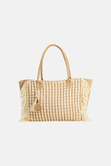 Sac à bandoulière beige de Access® en raphia tressé avec motif à picots crème, franges et breloque décorative.