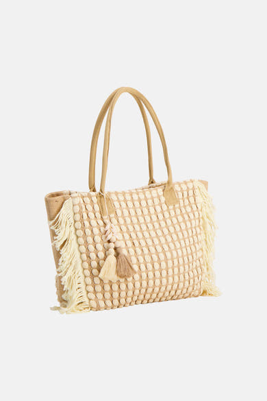 Sac à bandoulière beige de Access® tressé avec motifs en relief, franges et un charm à glands et perles.