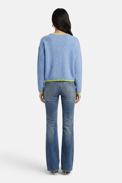Pull à col rond bleu de ADORE, avec bordure contrastée jaune fluo, porté avec un jean.