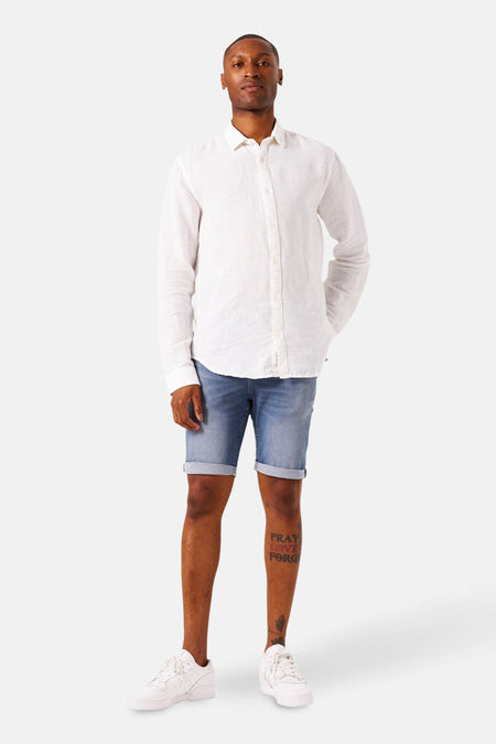 Short en jean denim bleu moyen de GARCIA, porté avec une chemise blanche à manches longues et des baskets blanches.