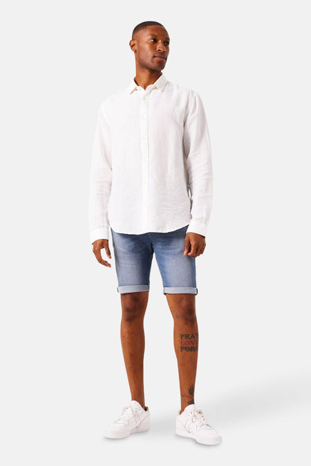 Short en jean denim bleu moyen de GARCIA, porté avec une chemise blanche à manches longues et des baskets blanches.