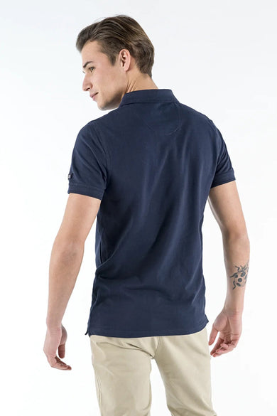 Polo bleu marine de PRESLY & SUN, avec manches courtes et pantalon beige.