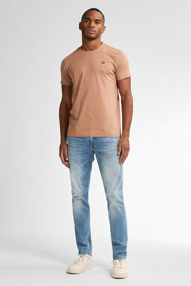 Slim jeans in denim van Petrol Industries, gedragen met een effen T-shirt en sneakers.