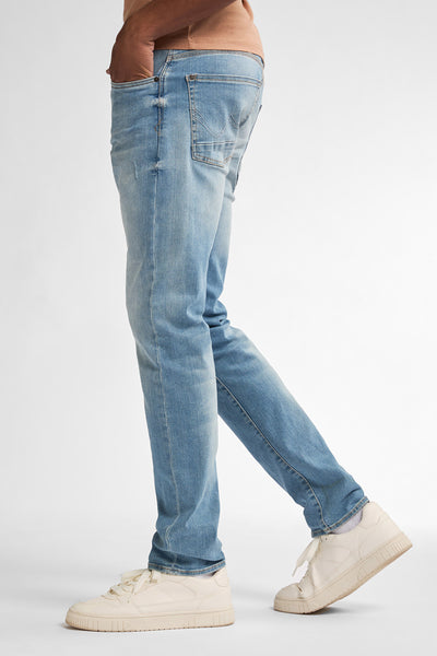 Jean slim en denim Petrol Industries®, porté avec des baskets blanches et un t-shirt beige.