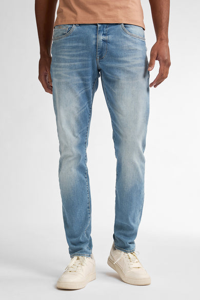 Slim jeans in blauwe denim van Petrol Industries, met wassing en crèmekleurige schoenen.