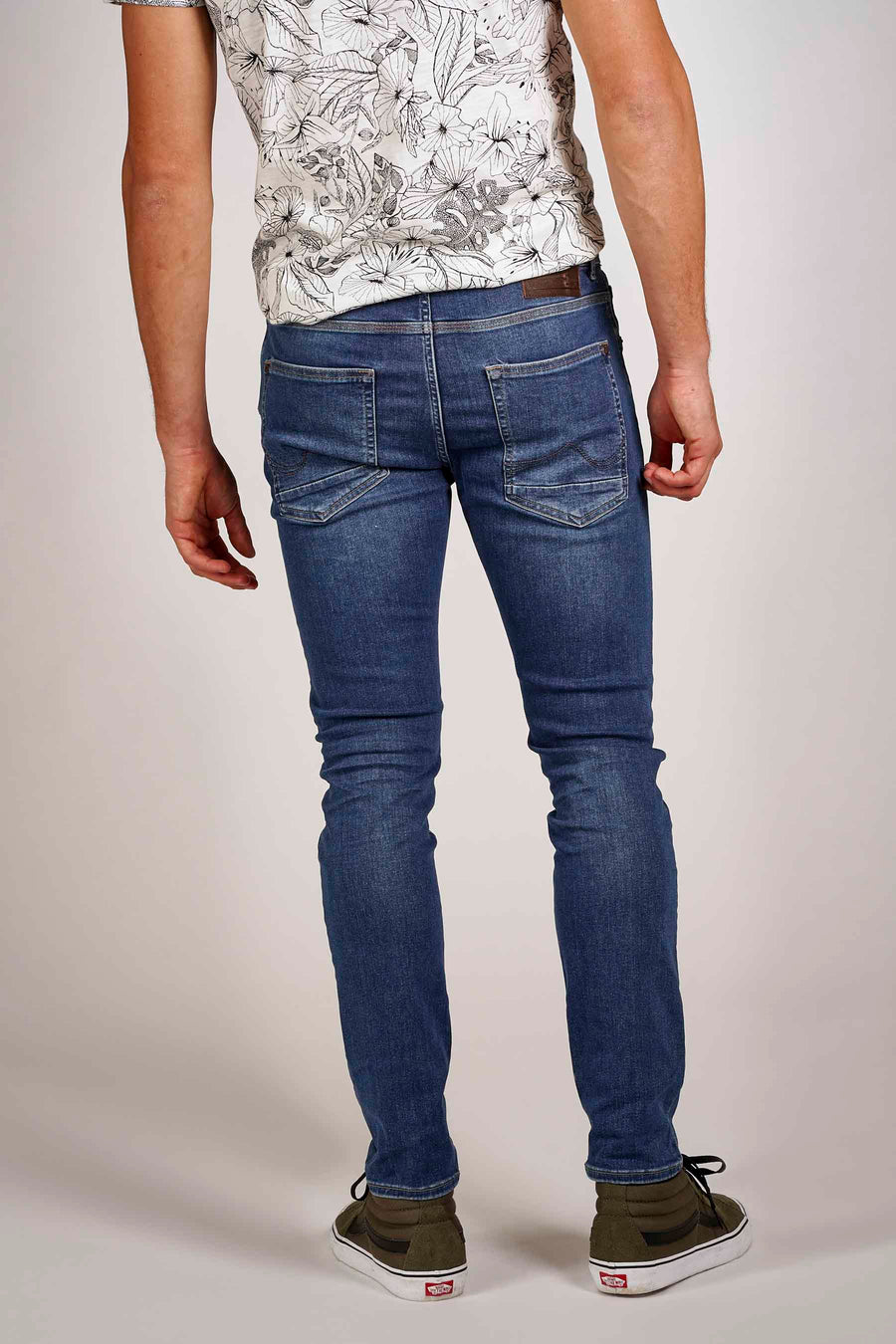 Blauwe slim fit jeans van Petrol Industries®, gedragen met een T-shirt met bloemenprint en hoge sneakers.