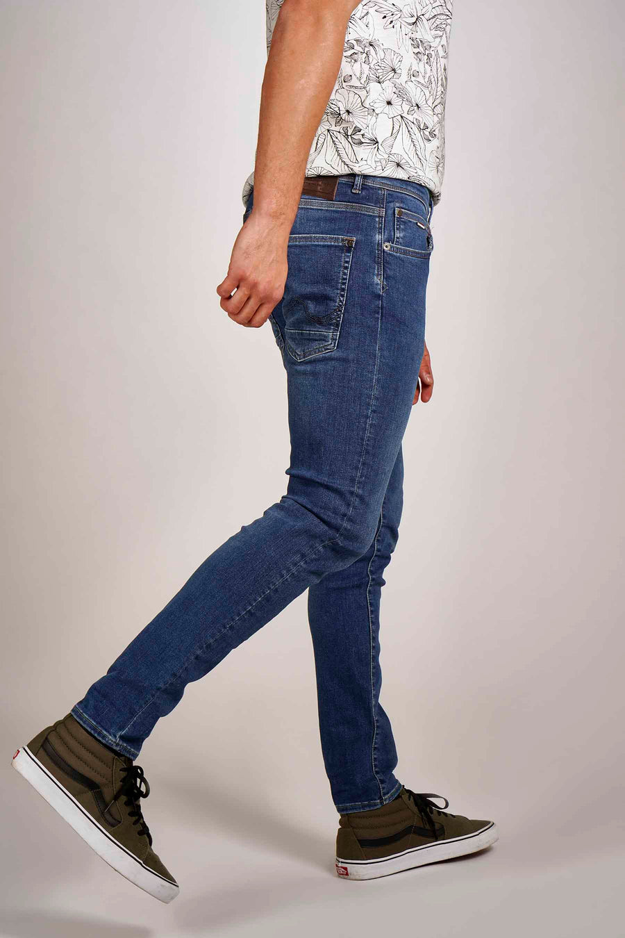 Blauwe slim fit jeans van Petrol Industries®, gedragen met een T-shirt met bloemenprint en hoge sneakers.