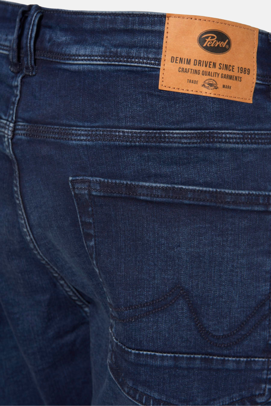Jean slim en denim bleu foncé de Petrol Industries, avec détails de surpiqûres et étiquette en cuir visible.
