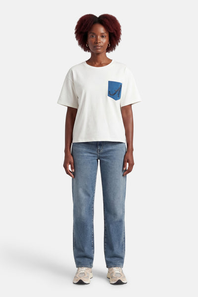 Wit T-shirt met korte mouwen van ADORE, met een versierde blauwe zak, gedragen met een spijkerbroek en sneakers.