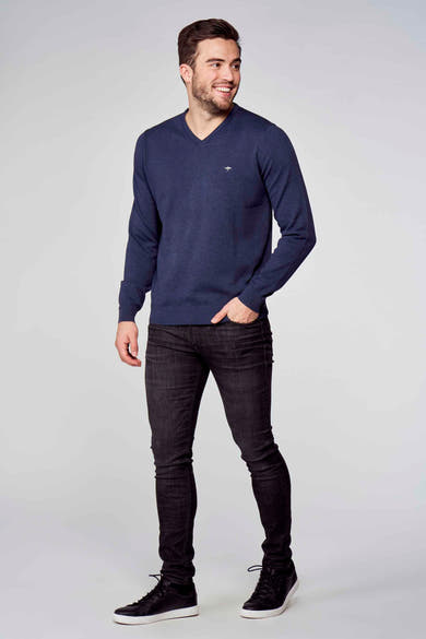 Pull col V bleu de Fynch-Hatton, porté avec un jean noir et des baskets noires à semelle blanche.