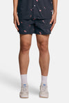 Short de bain bleu marine de LYLE & SCOTT à motif de poissons roses, porté avec des chaussettes blanches et des baskets claires.