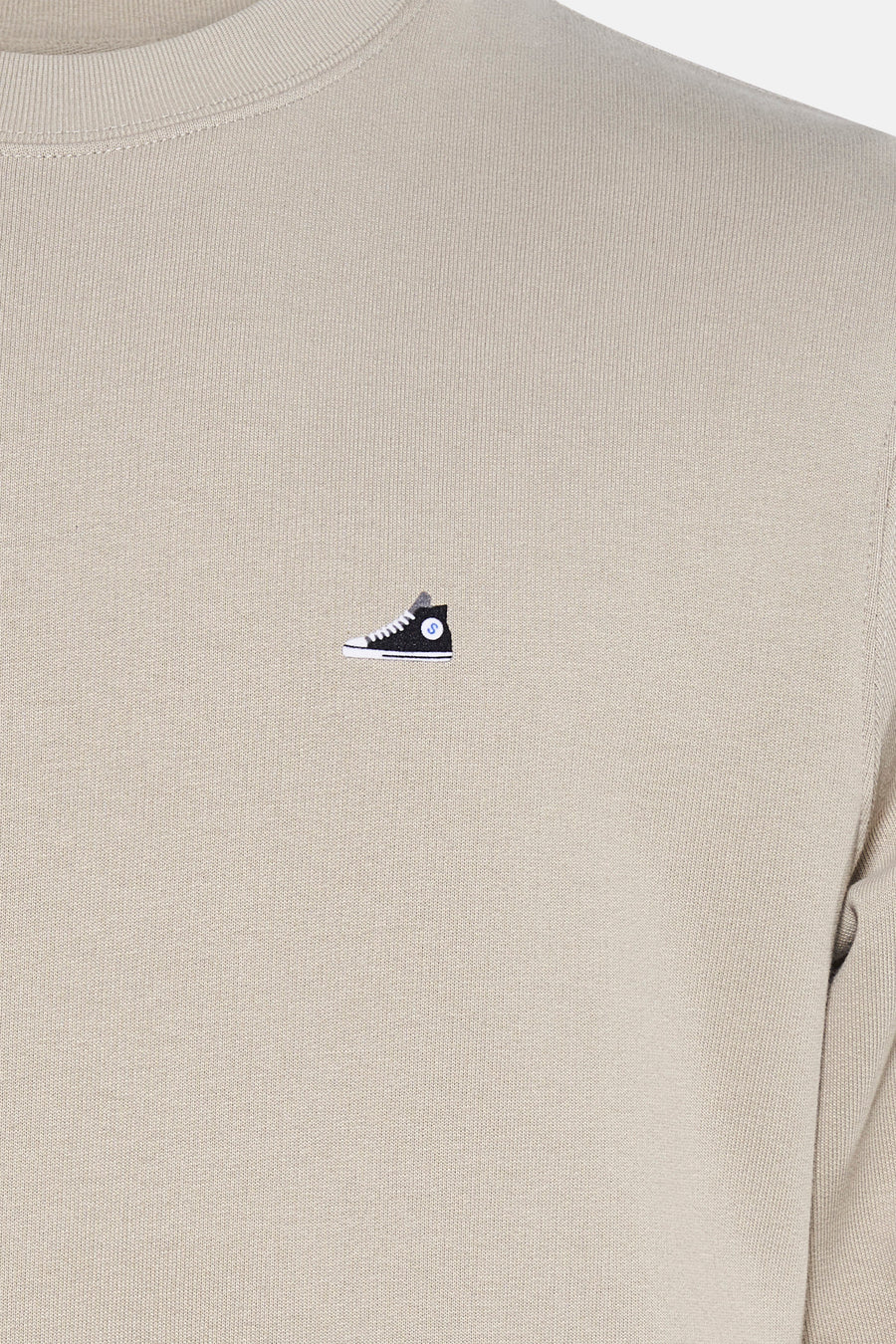 Beige sweater van STROM met een geborduurd motief van een hoge schoen op de voorkant.
