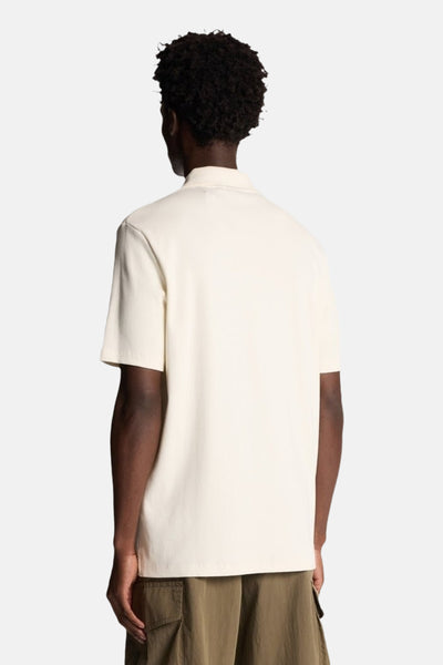 Polo beige à manches courtes de LYLE & SCOTT, vu de dos, porté avec un pantalon cargo kaki.