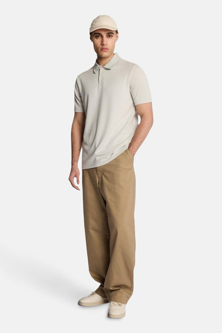 Grijze polo met korte mouwen van LYLE & SCOTT, gedragen met een wijde beige broek en een pet.