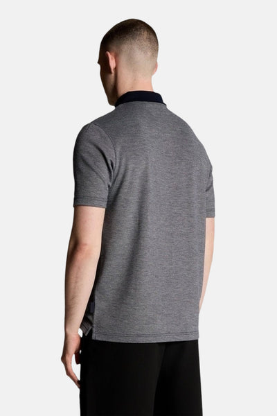 Blauw poloshirt met korte mouwen van LYLE & SCOTT, marineblauwe kraag, gemêleerde textuur, gedragen met een zwarte broek.