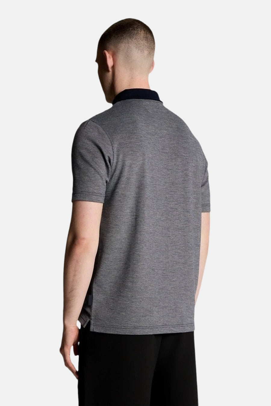 Polo à manches courtes bleu par LYLE & SCOTT, col marine, texture chinée, porté avec un pantalon noir.