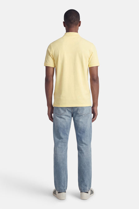 Gele polo van LYLE & SCOTT, gedragen met een blauwe jeans en sportschoenen.