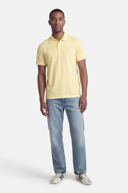 Gele polo van LYLE & SCOTT, gedragen met een blauwe jeans en witte sneakers.