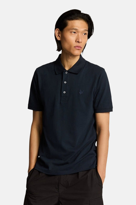 Blauw poloshirt met korte mouwen van LYLE & SCOTT, achterkant, gedragen met een zwarte cargobroek.