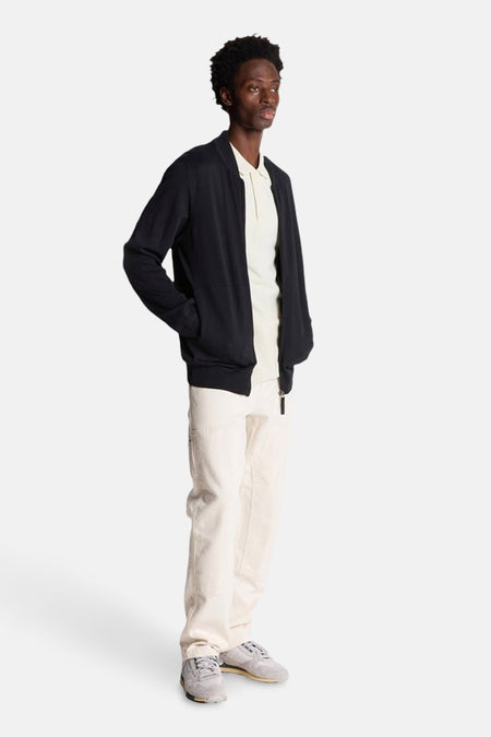 Grijs poloshirt met korte mouwen van LYLE & SCOTT, gedragen met een zwart jasje en een witte broek.