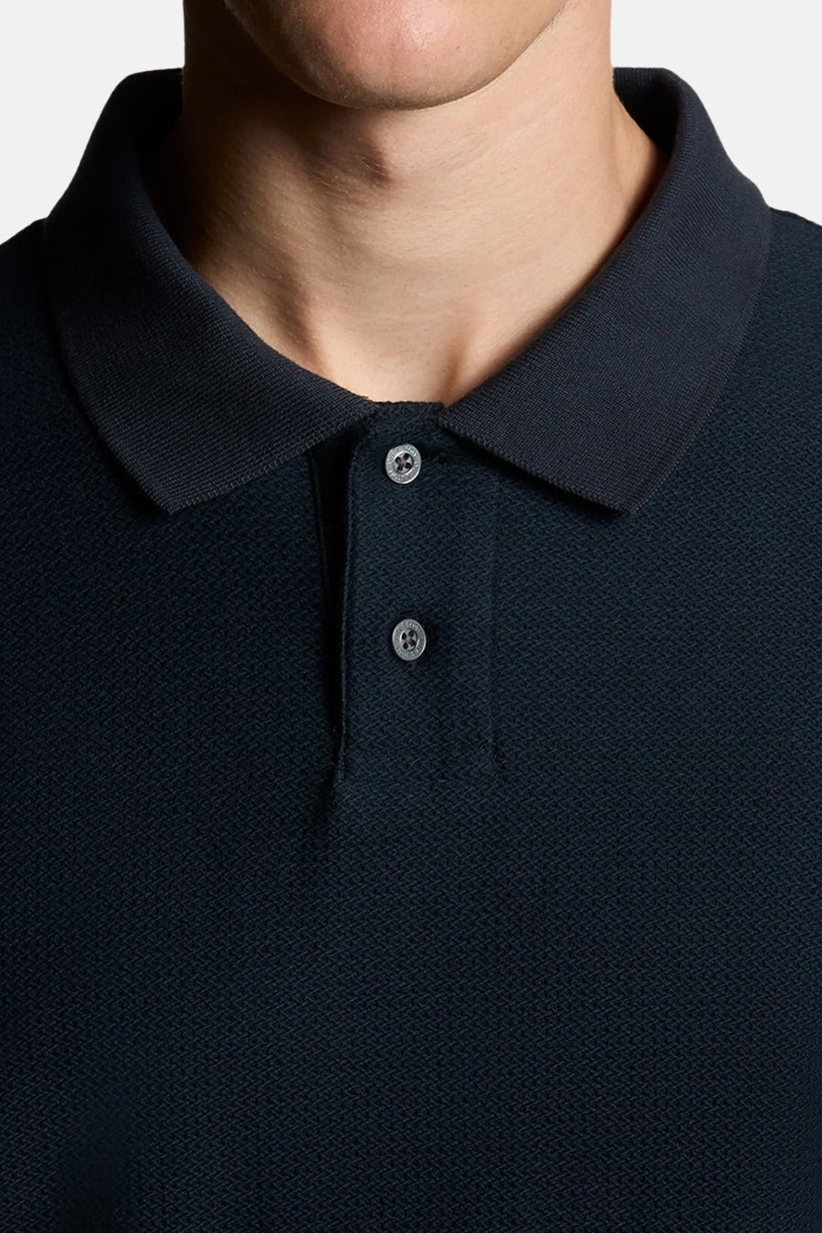 Polo bleu à manches courtes de LYLE & SCOTT, montrant une texture piquée et deux boutons visibles.