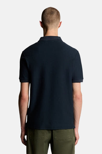 Polo bleu à manches courtes de LYLE & SCOTT, texture piquée, porté avec un pantalon vert olive, vue arrière.