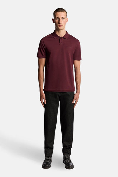 Bordeaux poloshirt met korte mouwen van Lyle & Scott, gedragen met een donkere broek en zwarte schoenen.
