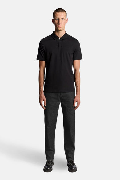 Zwart poloshirt met korte mouwen van LYLE & SCOTT, gedragen met een antracietgrijze broek en zwarte leren schoenen.