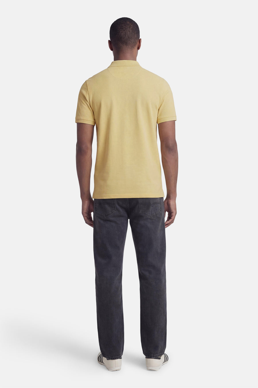 Groen poloshirt van LYLE & SCOTT, gedragen met een donkere jeans en gestreepte sneakers.